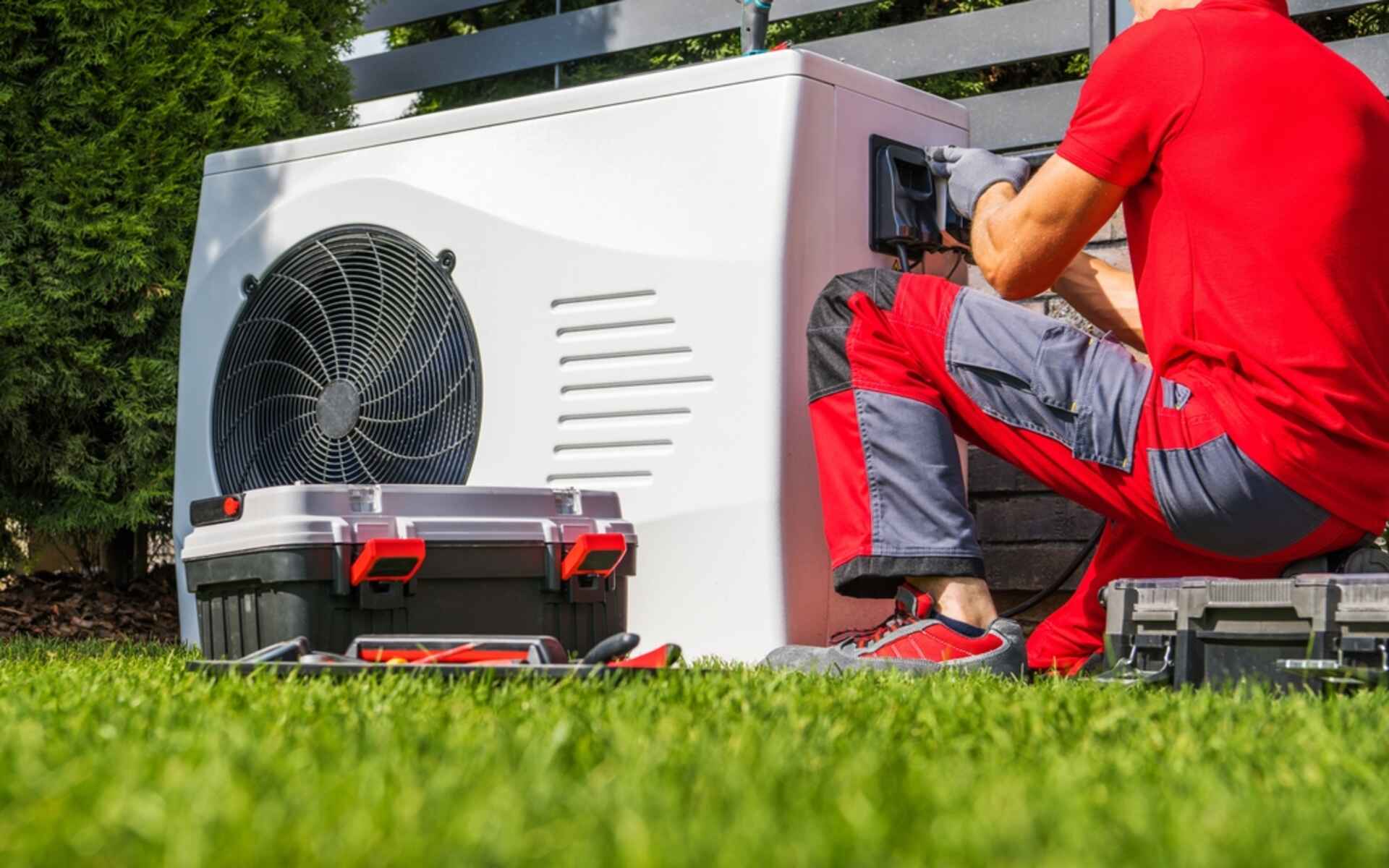 An HVAC technician installs an outdoor unit, showcasing the critical role of HVAC suppliers in providing necessary equipment and tools.