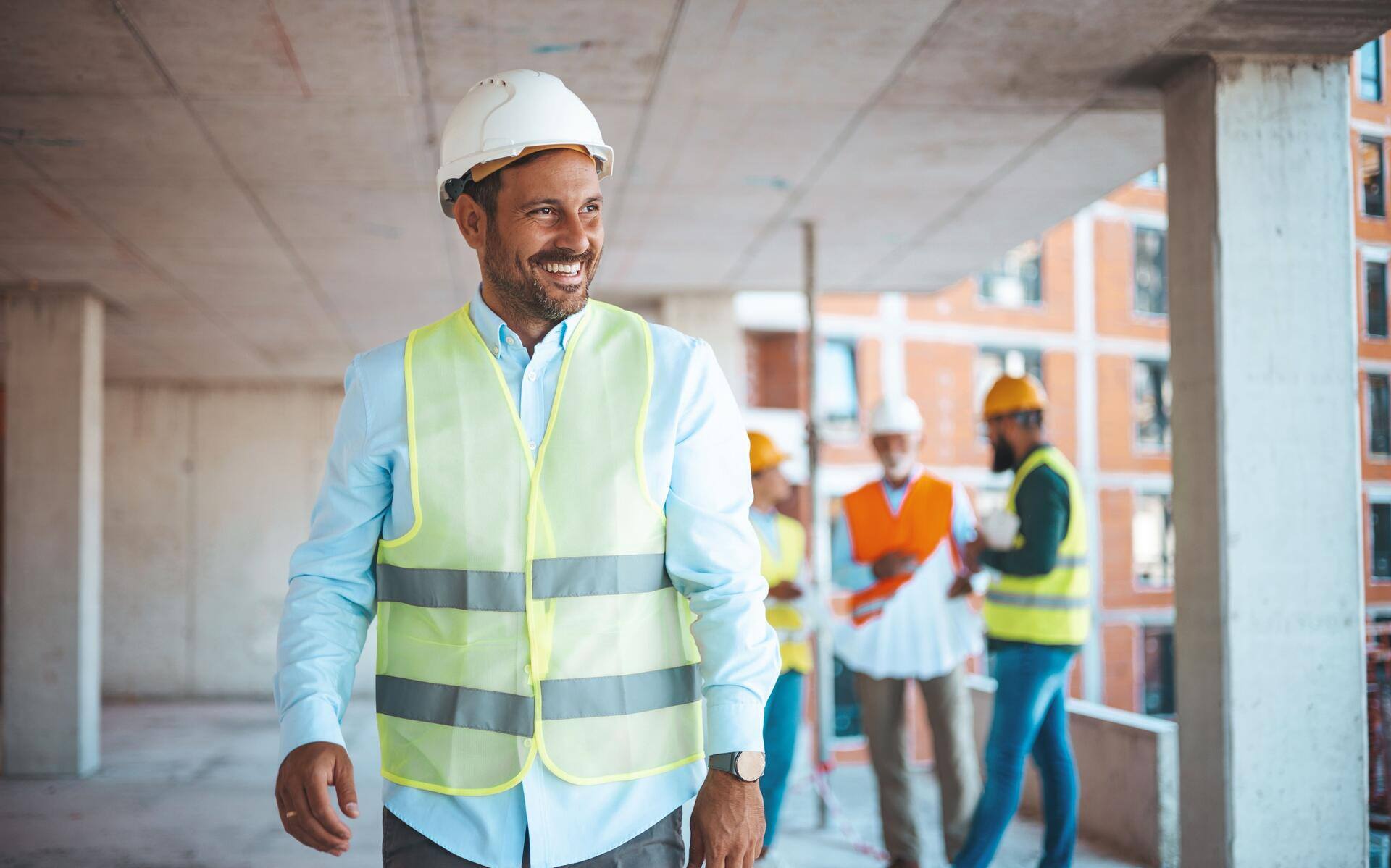 Smiling contractor in a reflective vest and hard hat at a construction site, representing contractor lead generation.