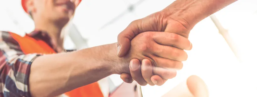 Man wearing PPI shaking hands with another man